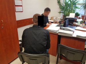 Policjant wykonuje czynności z zatrzymanym