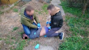 Na zdjęciu widać dwóch policjantów, którzy zakładają kajdanki mężczyźnie leżącemu na ziemi twarzą do dołu.