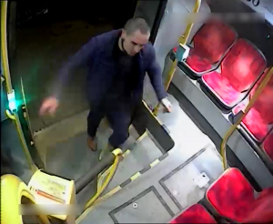 Zdjęcie przedstawia wsiadającego do autobusu mężczyznę. W tle widać siedzenia i kasownik.