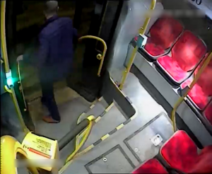 Zdjęcie przedstawia wysiadającego z autobusu mężczyznę. Drzwi autobusu są otwarte. Widać sylwetkę mężczyzny od tyłu.