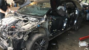 Zdjęcie przedstawia wnętrze garażu a w nim pojazd z zdemontowanymi częściami