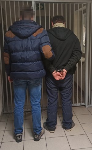 na zdjęciu widać zatrzymanego mężczyznę prowadzonego przez nieumundurowanego policjanta