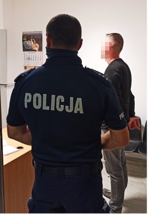 na zdjęciu widać policjanta w mundurze z zatrzymanym mężczyzną