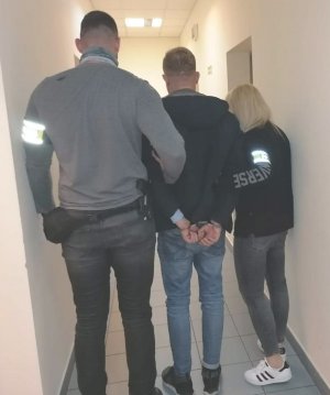 na zdjęciu widać policjanta i policjantkę po cywilnemu z zatrzymanym mężczyzną