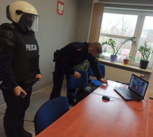 na zdjęciu widać dzielnicowego i policjantkę, która prezentuje elementy umundurowania