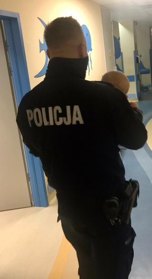 na zdjęciu widać policjanta z dzieckiem na rękach