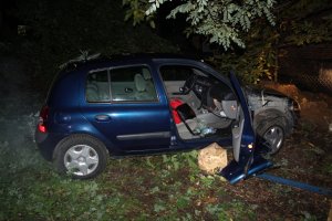 Zdjęcie przedstawia niebieski samochód osobowy. Stoi on prawą stroną do obiektywu. Ma otwarte prawe przednie drzwi pasażera