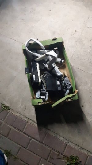 Zdjęcie przedstawia pomieszczenie garażowe, a w nim rozłożone na ziemi części samochodowe.