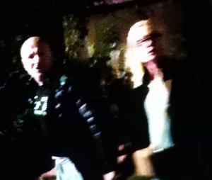 Zdjęcie przedstawia kobietę i mężczyznę. Kobieta w wieku około 35 lat, blond włosy sięgające do ramion, ubrana  w ciemną kurtkę.
Mężczyzna w wieku około 45 lat, krępej budowy ciała, łysy, ubrany w ciemną kurtkę pikowaną i ciemną bluzę.