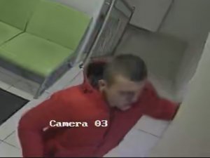 Zdjęcie przedstawia mężczyznę w czerwonej kurtce. W tle widać wyposażenie pomieszczenia w postaci zielonych mebli.