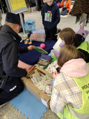 policjant rozdaje kolorowanki na dworcu