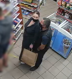 Zdjęcie przedstawia wnętrze sklepu. Widać w nim kobietę i mężczyznę, są w wieku około 45-55 lat, oboje prawdopodobnie narodowości romskiej.
Kobieta ma otyłą sylwetkę, ubrana była w czarną spódnicę, białe buty, czarną koszulę lub marynarkę, twarz zasłaniała jej czarna maseczka, w ręku trzymała papierową torbę na zakupy.
Mężczyzna jest normalnej budowy ciała, ubrany w czarne buty, czarne spodnie jeansowe, czarny bezrękawnik oraz granatowy t-shirt. W tle widać półki i regały z asortymentem.