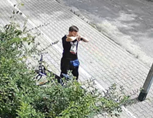 Zdjęcie przedstawia dwóch mężczyznę idącego chodnikiem, on ma około 25-30 lat, jest szczupłej budowy ciała, ma krótkie czarne włosy, ubrany jest w czarne spodnie dresowe, czarną koszulkę z krótkim rękawem.
