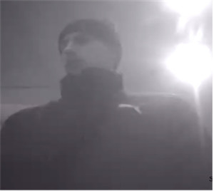 Zdjęcie jest z kamery monitoringu. Widać na nim ciemną sylwetkę mężczyzny ubranego w czapkę.