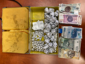 Zdjęcie przedstawia pudełko, a w nim srebrne zawiniątka z folii aluminiowej oraz ułożone obok pieniądze o nominałach 200 PLN, 100 PLN, 50 PLN, 20 PLN i 10 PLN.