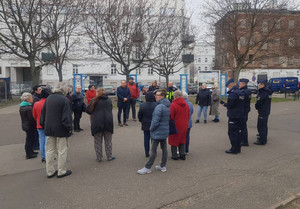 Zdjęcie przedstawia dzielnicowych w granatowych mundurach, którzy stoją na zewnątrz z mieszkańcami.