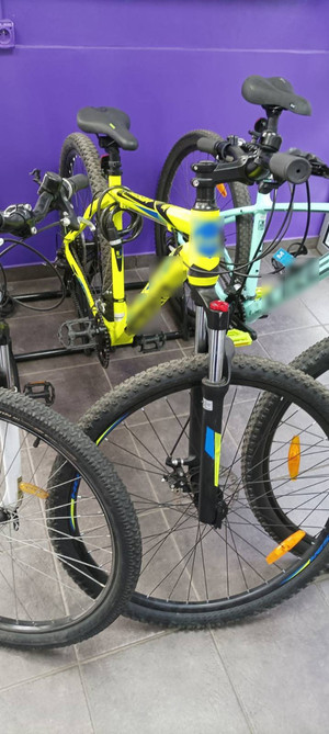 Zdjęcie przedstawia dwa stojące obok siebie rowery. Jeden z nich jest żółty, drugi w kolorze błękitnym. Na zdjęciu widać również fragment koła innego roweru.