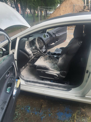 Zdjęcie przedstawia spalone wnętrze srebrnego samochodu. Szyba od przednich lewych drzwi od strony kierowcy jest wybita.