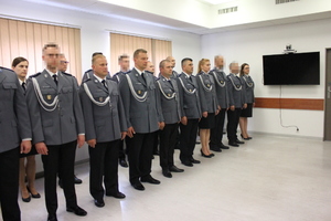 Zdjęcie przedstawia funkcjonariuszy stojących w dwóch rzędach na sali w uroczystych mundurach.