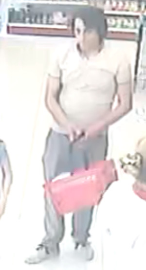 Zdjęcie przedstawia mężczyznę w wieku około 35-40 lat, około 175 cm wzrostu, czarne włosy; ubrany jest w białą bluzkę, jasne spodnie, białe buty. W rękach przed sobą trzyma koszyk zakupowy. Znajduje się wewnątrz drogerii. W tle widać półki z asortymentem.