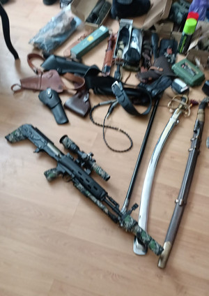 zdjęcie przedstawia leżące na podłodze szable, noże w etui, amunicję oraz pistolet pneumatyczny.