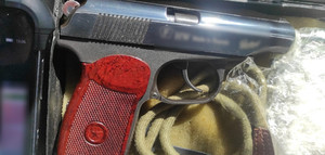 zdjęcie przedstawia czarną broń palną z czerwoną rękojeścią.