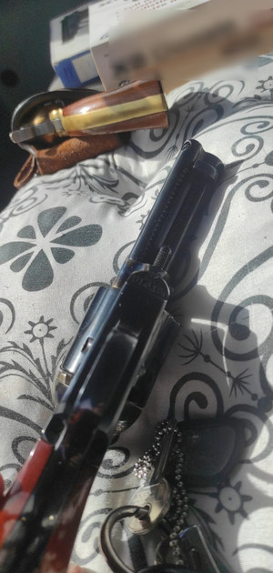 zdjęcie przedstawia czarną broń z czerwoną rękojeścią, przed nią widać mniejszą jednostkę broni w etui.