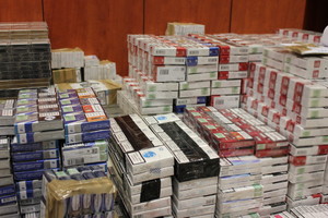 Zdjęcie przedstawia ułożone w stosy zabezpieczone paczki nielegalnych papierosów.