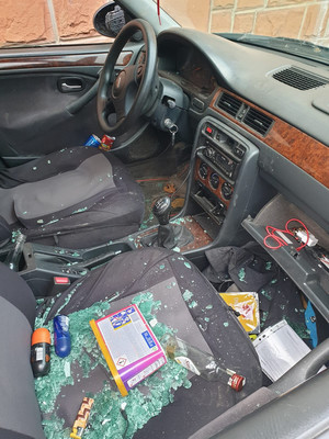 Zdjęcie przedstawia wnętrze zabezpieczonego pojazdu. Na prawym fotelu pasażera widać leżące przedmioty oraz fragmenty potłuczonego szkła.