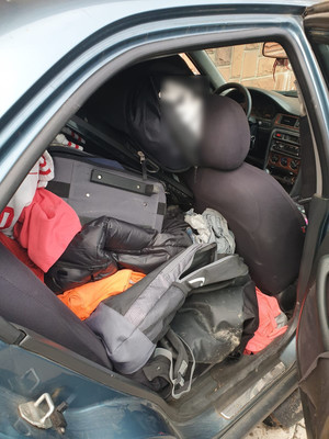 zdjęcie przedstawia otwarte prawe tylne drzwi od pasażera zabezpieczonego pojazdu. Na siedzeniu widać nagromadzone przedmioty, w tym odzież.