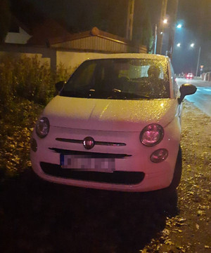 Zdjęcie przedstawia białego fiata 500 zaparkowanego wzdłuż ulicy.