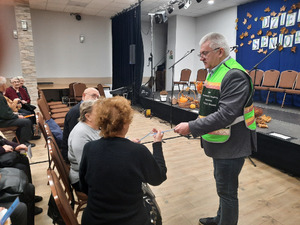 Zdjęcie przedstawia przedstawiciela BBiZK, który wręcza seniorom opaski odblaskowe.