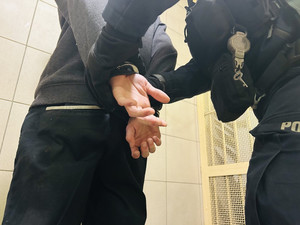Zdjęcie przedstawia dłonie w kajdankach i drugą parę rąk zbliżoną do nich.