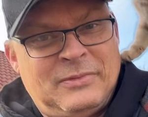 Zdjęcie przedstawia fragment twarzy mężczyzny, który ma okulary w grubych oprawkach.