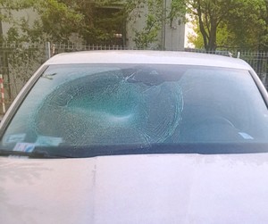 Zdjęcie przedstawia fragment samochodu z uszkodzoną przednią szybą.