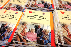 Zdjęcie przedstawia rozłożone na stole poradniki. Na stronie tytułowej widnieje napis &quot;Seniorze. Babciu, Dziadku...Nie daj się oszukać. Bądź bezpieczny!