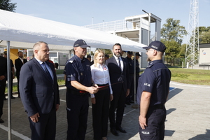 Zdjęcie przedstawia dwóch umundurowanych policjantów i osoby w cywilnych ubraniach stojące naprzeciwko siebie.