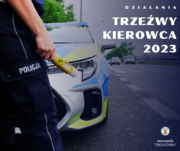 Zdjęcie przedstawia fragment sylwetki policjanta, który trzyma w prawej dłoni alkomat. W tle widać oznakowany radiowóz.