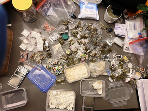 Zdjęcie przedstawia substancje różnej wielkości i w różnym kolorze umieszczone w przezroczystych torebkach i umieszczone na blacie biurka wśród innych przedmiotów.