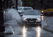 Zdjęcie przedstawia auto osobowe jadące ulicą. Spod jego kół widać uciekającą wodę.
