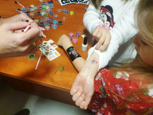 Zdjęcie przedstawia dwie dziecięce dłonie, na których widać brokatowe tatuaże.