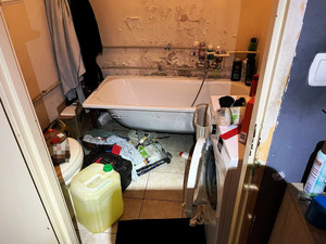 Zdjęcie przedstawia wnętrze łazienki z wanną, na podłodze stoją pojemniki z różnymi substancjami.