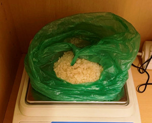 Zdjęcie przedstawia białą substancję znajdującą się w foliowej zielonej  torebce ułożonej na stalowym podłożu wagi.
