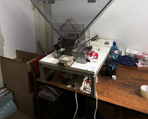 Zdjęcie przedstawia maszynę ustawioną na stole służącą do produkcji papierosów.