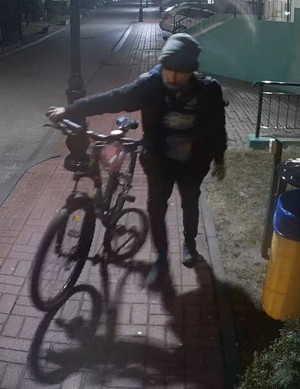 Zdjęcie przedstawia mężczyznę prowadzącego nocą rower.