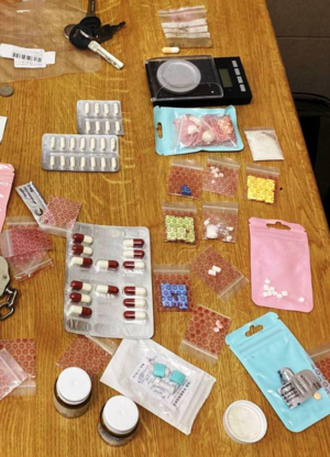 Zdjęcie przedstawia przedmioty rozłożone na stole. Są wśród nich torebki z substancjami w różnych kolorach.