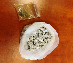 Zdjęcie przedstawia srebrne zawiniątka zapakowane w foliową torebkę, wyżej widać przezroczystą torebeczkę z substancją.