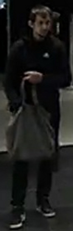 Mężczyzna ma około 175 cm wzrostu, czarne krótkie włosy, szczupłą budowę ciała. Ubrany jest w czarną bluzę z widocznym logiem „Adidas”, czarne spodnie, czarne buty z białym paskiem przy podeszwie oraz widocznym białym logiem „Nike”, w dłoniach trzyma szarą torbę.