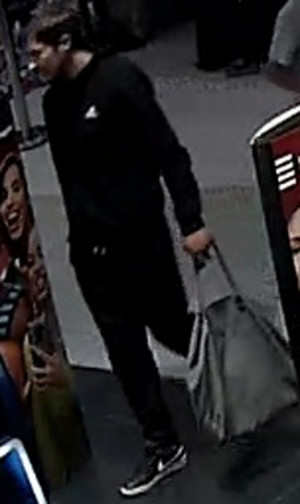 Mężczyzna ma około 175 cm wzrostu, czarne krótkie włosy, szczupłą budowę ciała. Ubrany jest w czarną bluzę z widocznym logiem „Adidas”, czarne spodnie, czarne buty z białym paskiem przy podeszwie oraz widocznym białym logiem „Nike”, w dłoni trzyma szarą torbę.