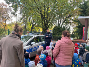 Zdjęcie przedstawia dzieci i ich opiekunów zgromadzonych wokół radiowozu.